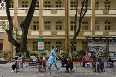 Los residentes, que usan mascarillas como medida preventiva contra la propagación del coronavirus, practican el distanciamiento social mientras esperan ser examinados en un improvisado centro de pruebas rápidas cerca del hospital Bach Mai en Hanoi el 31 de marzo de 2020