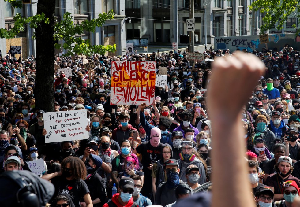 Un manifestante levanta el puño mientras centenares de personas se dirigen hacia el Ayuntamiento de Seattle. 