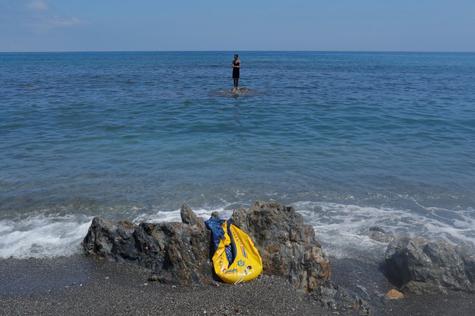 Un joven permanece subido a una roca frente a la playa del Tarajal, en la frontera de Ceuta. La llegada de personas a nado y a pie ha sido constante durante todo el lunes y continúa en la mañana de este martes en la misma playa donde se han desplegado tanques.