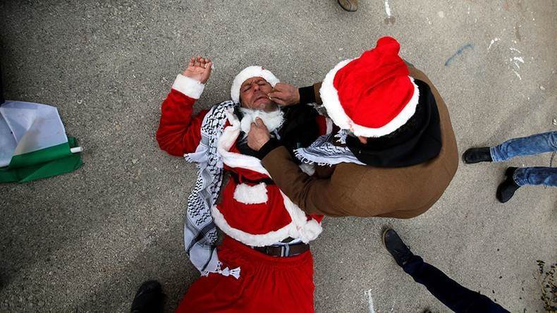 Un palestino vestido con el disfraz de Papá Noel sofocado luego de inhalar el gas lacrimógeno disparado por la ocupación israelí 